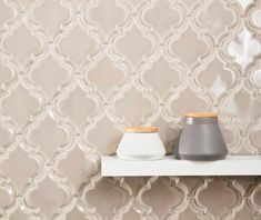 two vases sitting on a shelf in front of a wallpapered background with white and grey designs