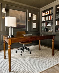 a desk with a lamp on it in front of a book case and bookshelves