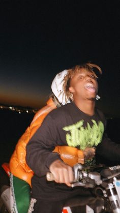 a young man riding on the back of a motorcycle at night with his mouth open