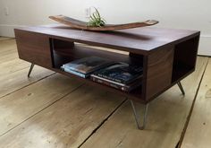 a coffee table with a boat on top and books under it, sitting on a wooden floor