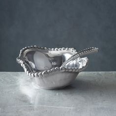 a silver bowl sitting on top of a table next to a gray wall and floor