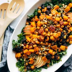 a white plate filled with vegetables and nuts on top of a blue napkin next to a wooden spoon