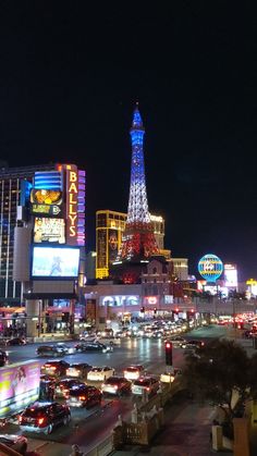 the las vegas strip at night with neon lights and cars driving down the street in front of the eiffel tower