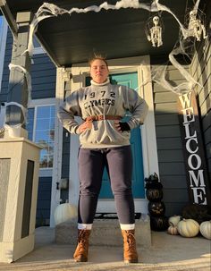 a woman standing in front of a house decorated for halloween