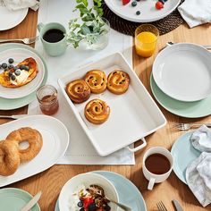 a wooden table topped with plates and bowls filled with pastries on top of it