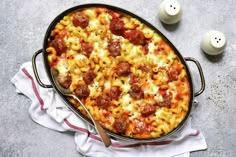 a large casserole dish with meatballs and cheese on the side next to two eggs