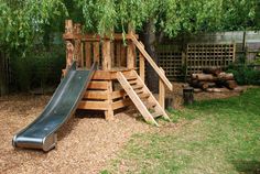 a wooden play structure with a slide in the middle