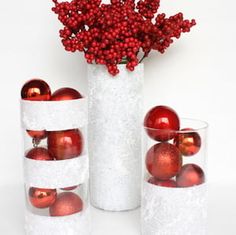 there are three vases with red ornaments in them and one is filled with balls