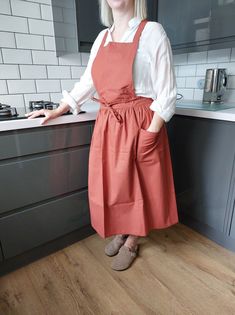 a woman wearing an orange apron standing in a kitchen