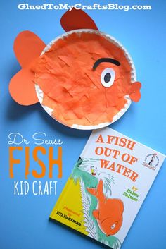 a paper plate with a fish cut out of it next to a children's book