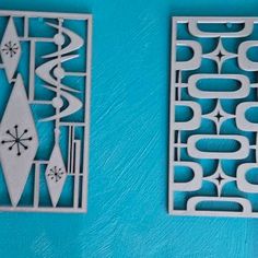 two pieces of paper cut out to look like geometric designs on a blue wall with white trim