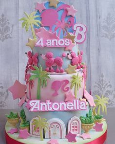 a three tiered cake decorated with pink and blue icing, palm trees, and poodles