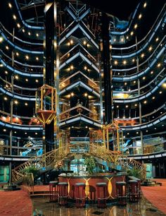 the inside of a building with many tables and chairs in front of it at night