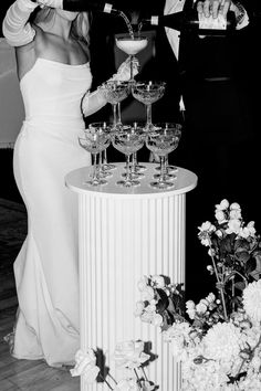 a man and woman standing next to each other with wine glasses in front of them