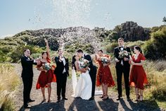 a group of people standing next to each other on a dirt road with confetti in the air