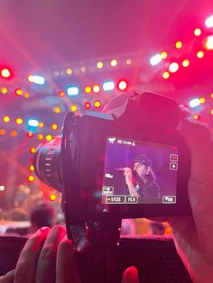 a person holding up a camera in front of a stage with red and blue lights