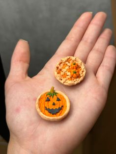 two miniature pumpkin pies sitting on someone's hand