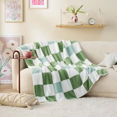 a green and white checkered blanket sitting on top of a couch next to a potted plant