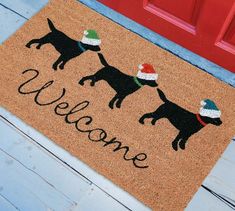 a welcome mat with three dogs wearing christmas hats on it and the words welcome written in black