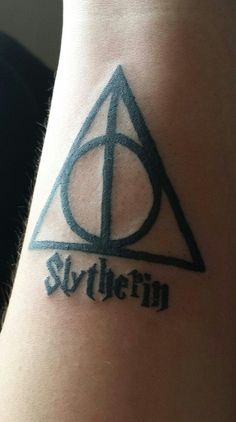 a harry potter symbol tattoo on the wrist is shown in black and grey ink, which reads slyffinn