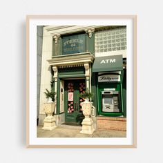 an atm in front of a building with potted plants on the outside and green doors