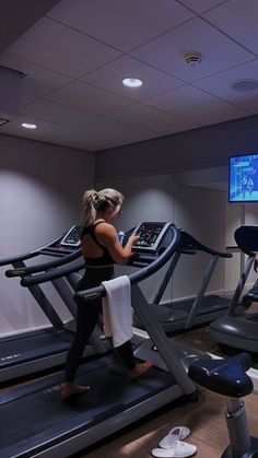 two women running on treadmills in a room with a flat screen tv above them