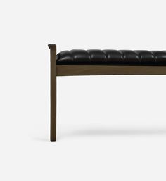 a black leather bench sitting on top of a wooden frame