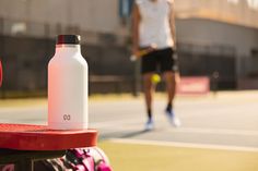 a white water bottle sitting on top of a red table next to a tennis racket