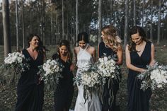 a group of women standing next to each other holding bouquets filled with white flowers