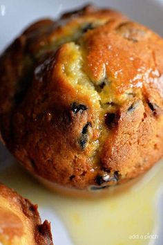 two muffins sitting on top of a white plate covered in melted yellow sauce