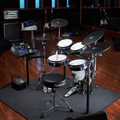 a drum set up on a rug in a room with wood flooring and lighting