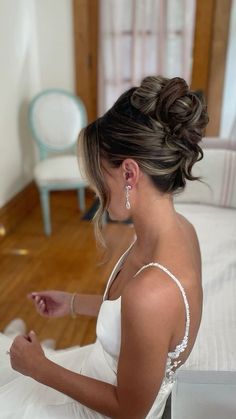 a woman sitting on top of a bed wearing a wedding dress and holding a cell phone