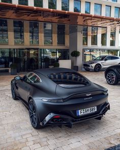 two black sports cars parked in front of a building