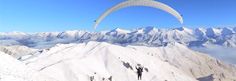 two people are paragliding over the snow covered mountains