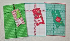 three christmas tags hanging from clothes pins on top of lined notebooks with writing paper attached to them