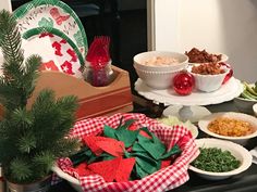 a table topped with plates and bowls filled with food next to a potted christmas tree