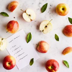 some apples and leaves on a table with a note