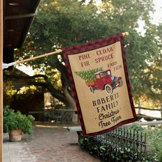 a sign hanging from the side of a building next to a brick walkway and trees