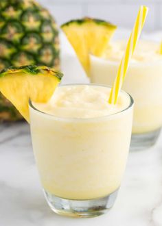 two glasses filled with pineapple smoothie on top of a table