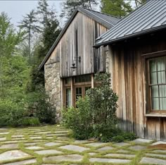 an old wooden house with stone walkways and grass