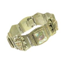 1960s Mexico Taxco alpaca silver bracelet. Hinged curved platforms. some engraved around bezel-set squares of polished abalone, alternating with carved abalone Mayan deity heads embellished w/ twisted rope headdresses and silver half-globes. Intricate hand workmanship and gleaming iridescent abalone make this a singular and striking artifact. Exceptional condition, and much more vibrant in person. Signed "Made Taxco Alpaca". Elegant Carved Rectangular Jewelry, Carved Silver Rectangular Jewelry, Carved Rectangular Silver Jewelry, Silver Carved Rectangular Jewelry, Silver Rectangular Carved Jewelry, Ceremonial Silver Art Deco Jewelry, Vintage Formal Jewelry With Inlay, Antique Rectangular Carved Jewelry, Formal Vintage Jewelry With Inlay