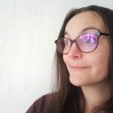 a woman wearing glasses and looking off to the side with her head tilted back, in front of a white wall