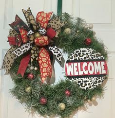 a leopard print wreath with the word welcome hanging on a front door decorated for christmas