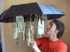 a man holding an umbrella with money hanging from it