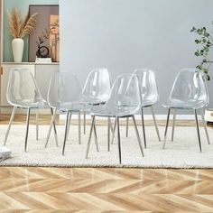 four clear chairs sitting on top of a hard wood floor next to a white rug