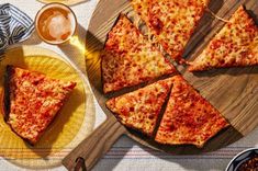 slices of cheese pizza on plates next to glasses of beer and condiments with spoons