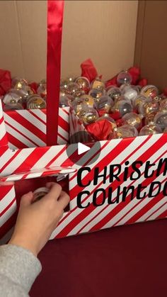 a person opening a christmas gift box with red and white stripes