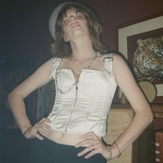 a woman wearing a white top and black skirt standing in front of a dresser with her hands on her hips