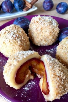 plums and blueberries are cut in half on a purple plate with powdered sugar