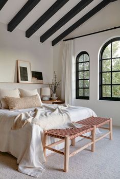 a large bed sitting under two windows in a bedroom